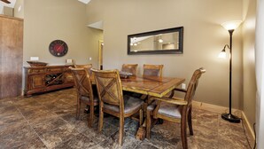 Un coin repas avec une table et des chaises en bois, une horloge et un miroir au mur.