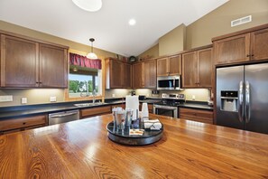 Een moderne keuken met houten kastjes, roestvrijstalen apparatuur en een centraal eiland met een dienblad.