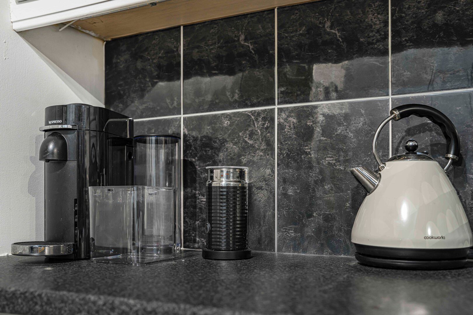 Een aanrecht met een koffiezetapparaat, een waterkoker en een thermosfles.