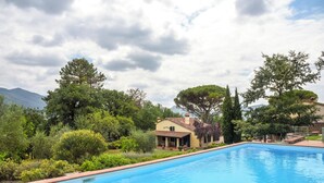 A rectangular swimming pool with a tiled edge, surrounded by lush greenery and a house with a tiled roof. - Ancient barn in Tuscan countryside near Florence (Le Fornaci)