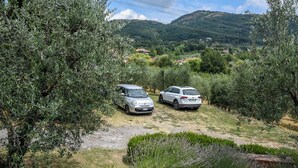 Two cars parked in a rural area with olive trees and a hilly landscape in the background. - Ancient barn in Tuscan countryside near Florence (Le Fornaci)