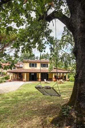 Ein Haus mit Terrasse, einer Schaukel und einem Rasen.