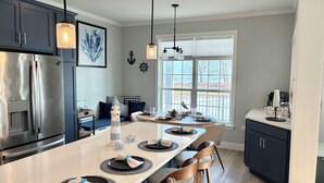 A modern kitchen with a central island, dark cabinets, stainless steel appliances, and pendant lighting. - Perfect 3-bedroom house with AC in soothing Waterview @ Baypoint (Lakeside Marblehead)