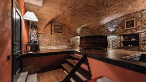 A rustic room with a sloped ceiling, a piano, a fireplace, and a stone wall. - Loft with Stone vaults in Villa Storica (Matraia)