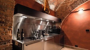 A modern kitchen with stainless steel appliances, a brick wall, and a curved ceiling. - Loft with Stone vaults in Villa Storica (Matraia)