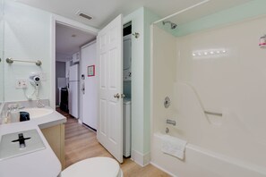 A bathroom with a toilet, sink, shower, and a door leading to a laundry area. - The Grand Turk | Spectacular Sunset View, Private (Key West)