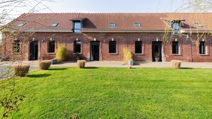 A red-brick building with a sloped roof, multiple windows, and a well-maintained lawn. - Holiday Home 'Gite Clémentine' with Private Terrace, Shared Garden and Wi-Fi (Baromesnil)