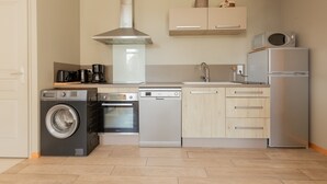 A compact kitchen with a washing machine, dishwasher, oven, microwave, and refrigerator. - Holiday Home 'Gite Clémentine' with Private Terrace, Shared Garden and Wi-Fi (Baromesnil)