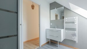 Ein modernes Badezimmer mit einem weißen Waschtisch, einem Handtuchhalter und einem Spiegel.