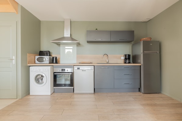 A compact kitchen with a washing machine, dishwasher, oven, microwave, and a refrigerator.