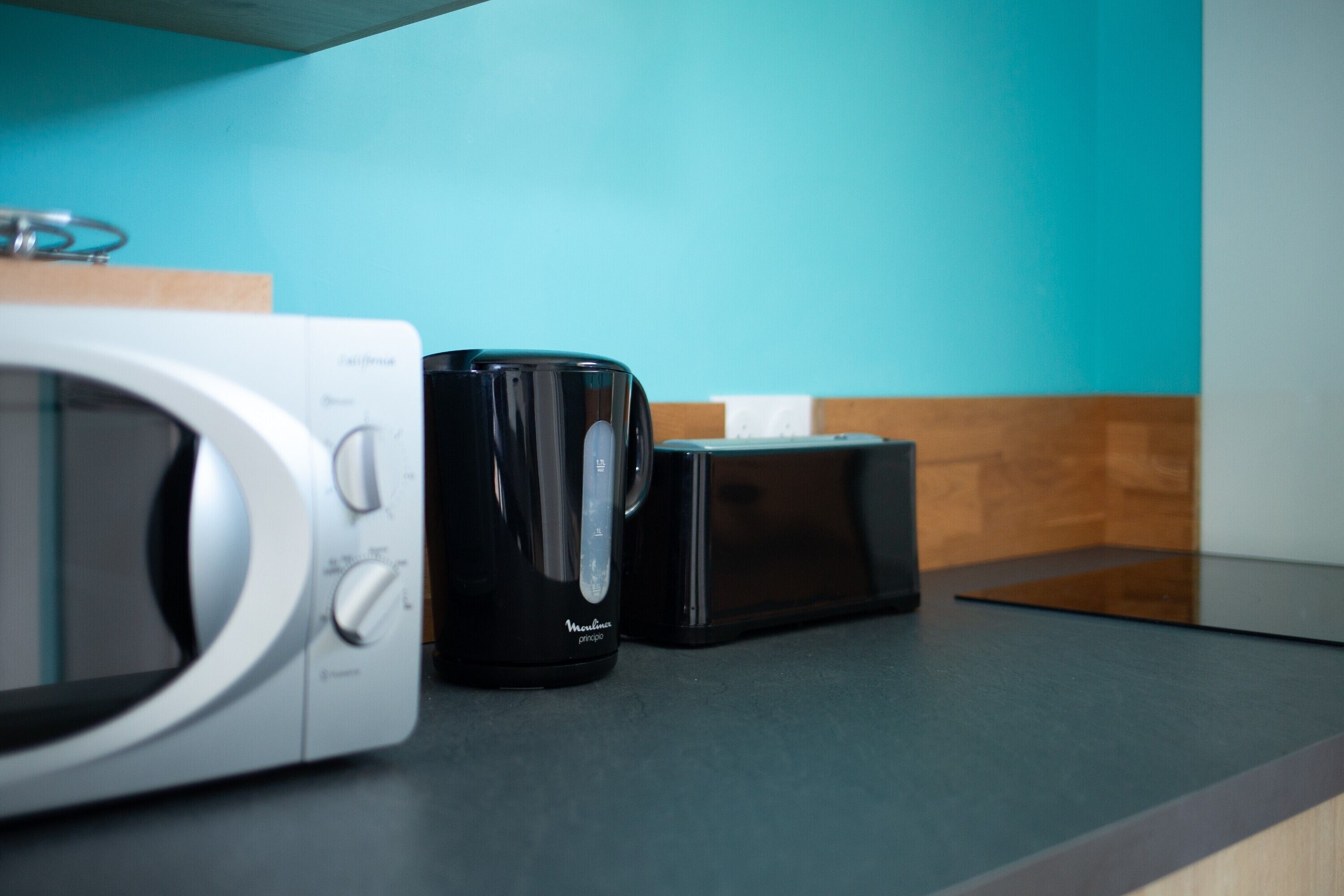 A kitchen with a microwave, a black coffee maker, and a toaster on a countertop.
