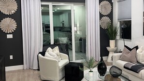 Ein modernes Wohnzimmer mit Deckenventilator, Glastisch und Sofa.