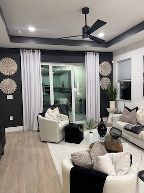 A modern living room with a ceiling fan, a glass coffee table, and a sofa. - 
Resort-Style 3BR 2 Living Rooms, TVs in Every Bedroom & Steps to the Pool. (Naples)