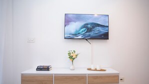 A white console table with a flat-screen TV mounted above it, displaying a wave.