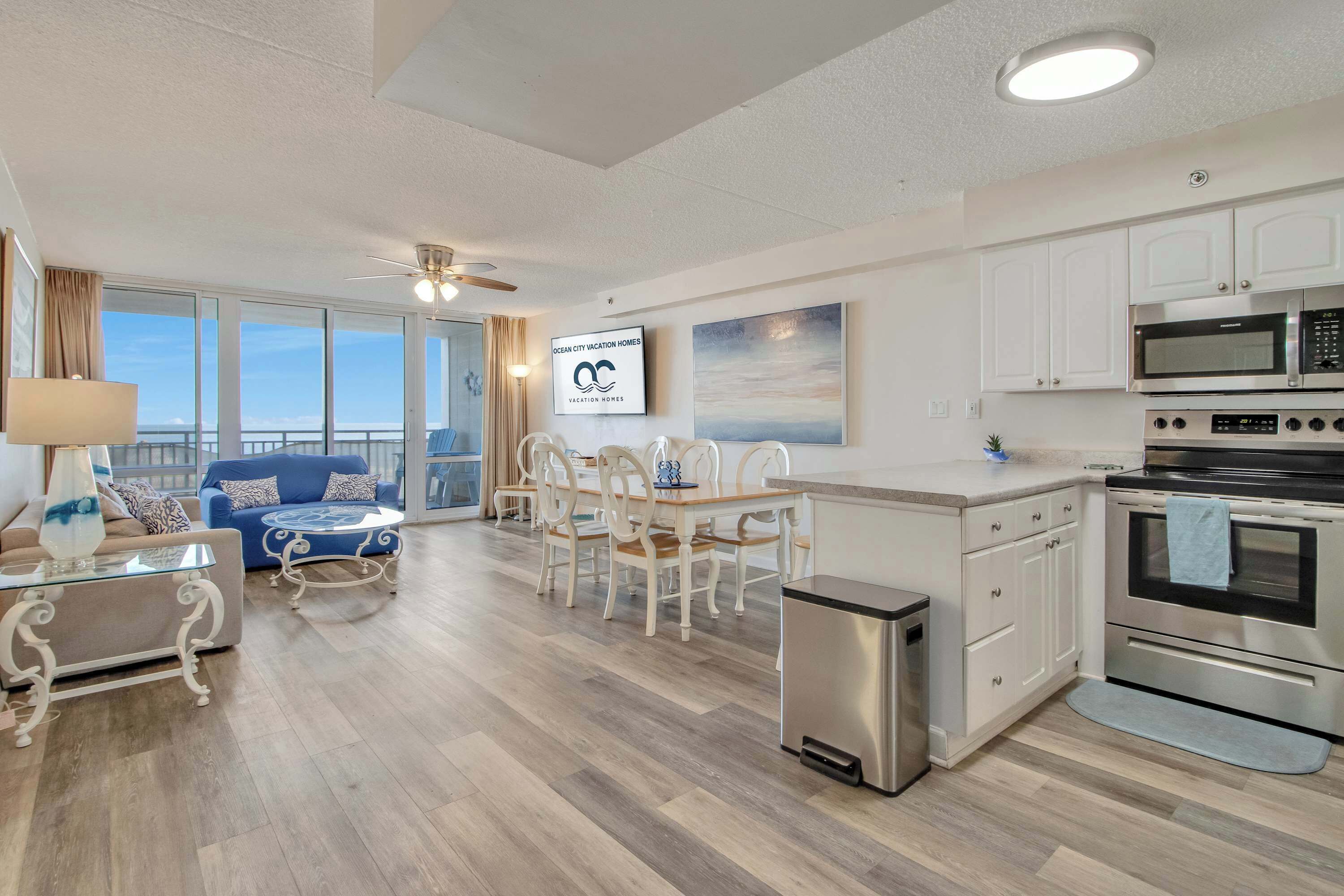 A modern kitchen with white cabinets, stainless steel appliances, and a dining area with a white table and chairs.