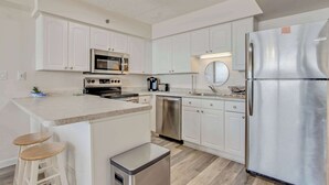 Una cocina moderna con armarios blancos, electrodomésticos de acero inoxidable y una isla central con taburetes.