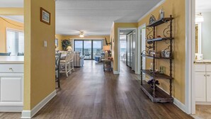 Un pasillo amplio con comedor, vista al exterior y un estante decorativo con varios objetos.