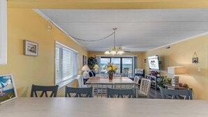Un comedor con una mesa y sillas, una lámpara colgante y vistas a través del ventanal.