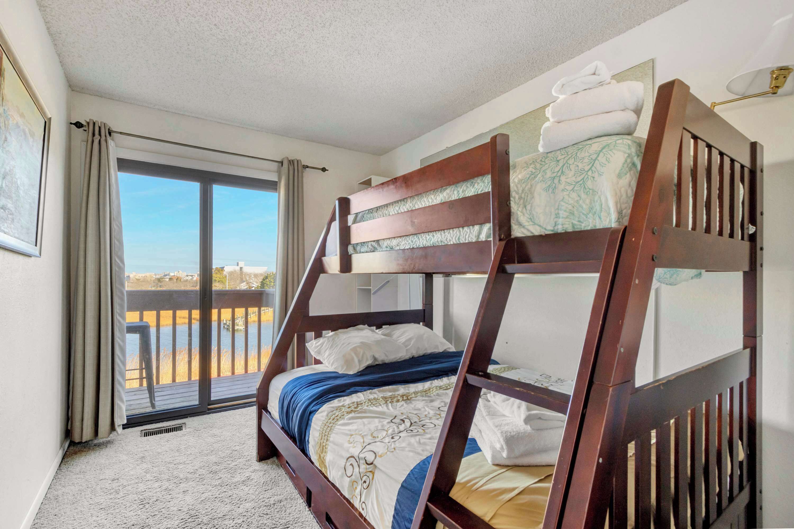 A bunk bed in a room with a view of a body of water through a sliding door.
