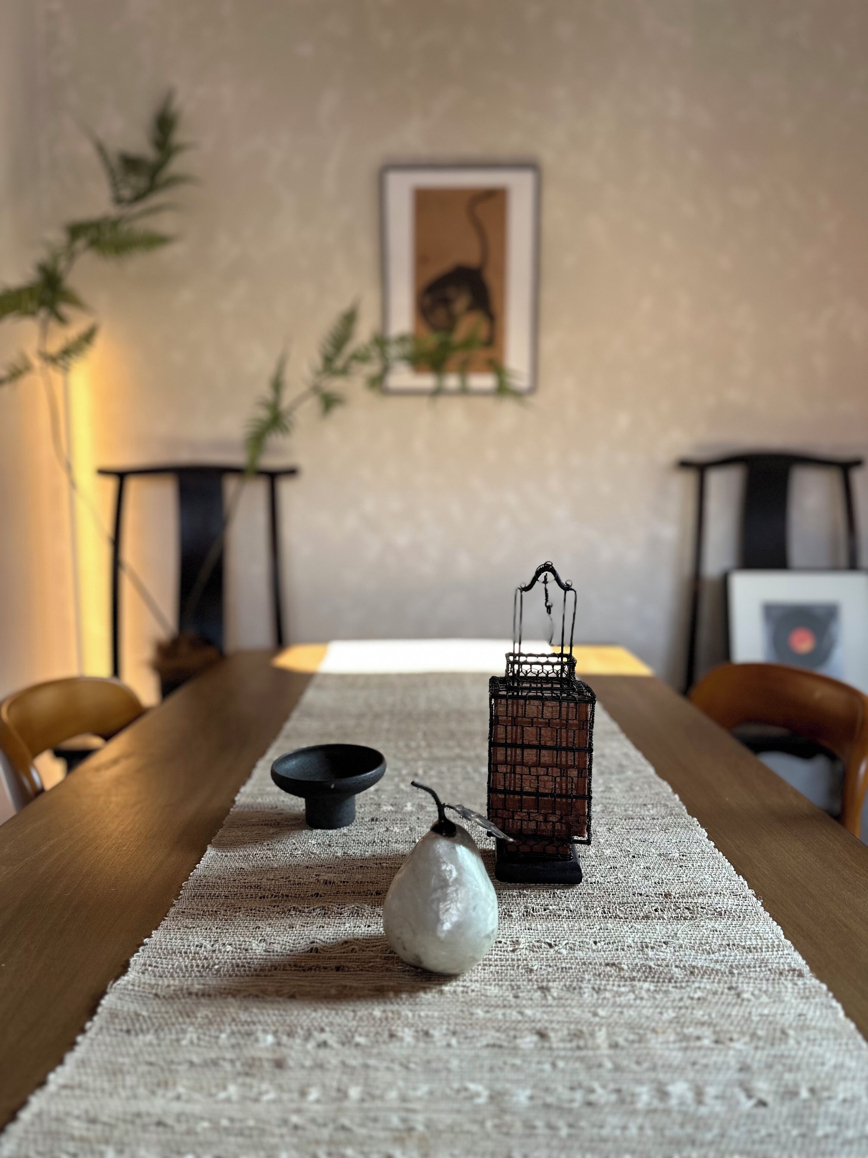 Ein Esstisch mit Untertasse, einer Birne, einem Kerzenständer und einer kleinen schwarzen Schüssel.