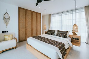 Een moderne slaapkamer met een groot bed, een houten garderobe, een nachtkastje en een hanglamp.