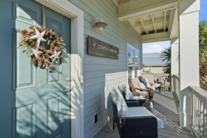 A porch with wicker furniture, a starfish decoration, and a sign reading "LIGHTLY SALTED." - Lightly Salted (Gulf Shores)