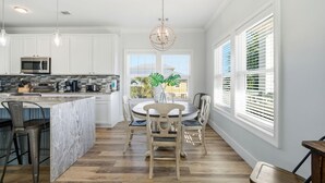 Una cocina moderna con armarios blancos, una isla central y un comedor con una mesa redonda y sillas.