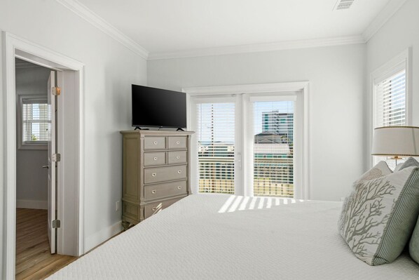 A bedroom with a bed, a dresser, a television, and a window with blinds. - Lightly Salted (Gulf Shores)