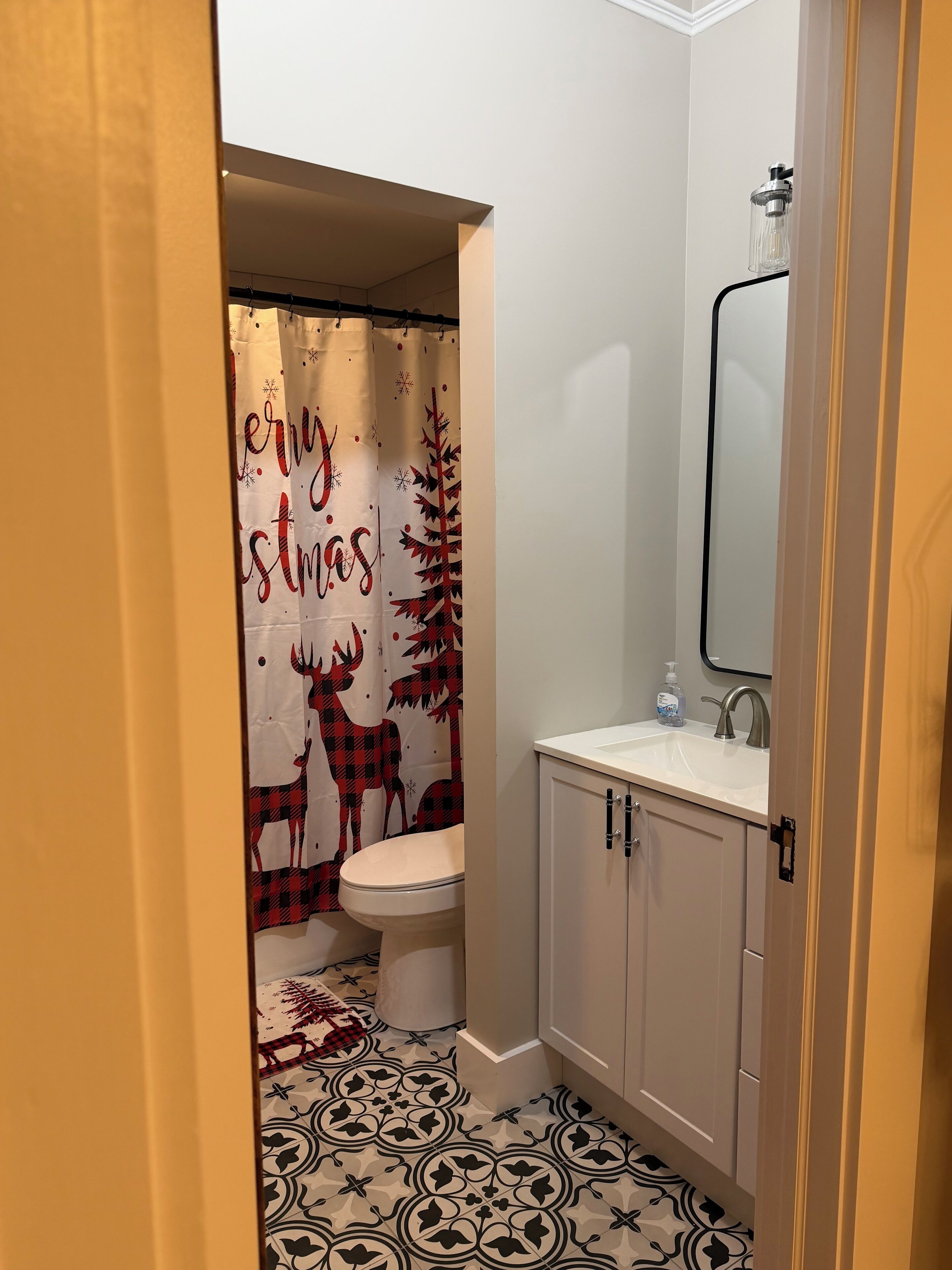 Une salle de bain comprenant des toilettes, un lavabo et une douche avec une pomme de douche protégée par une paroi en verre.
