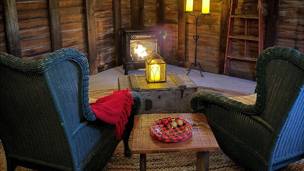 Ein gemütliches Blockhaus-Interieur mit Kamin, Lichterkette und rustikalen Holzwänden.