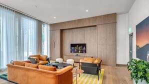 A modern living room with a sofa set, a coffee table, and a TV mounted on the wall. - Luxury Studio · Balcony + Rooftop Pool, Downtown (Miami)