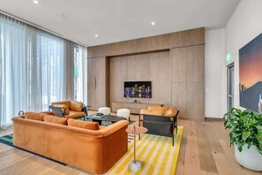 A modern living room with a sofa set, a coffee table, and a TV mounted on the wall. - Brand New Luxury Studio · Downtown Miami Skyline (Miami)
