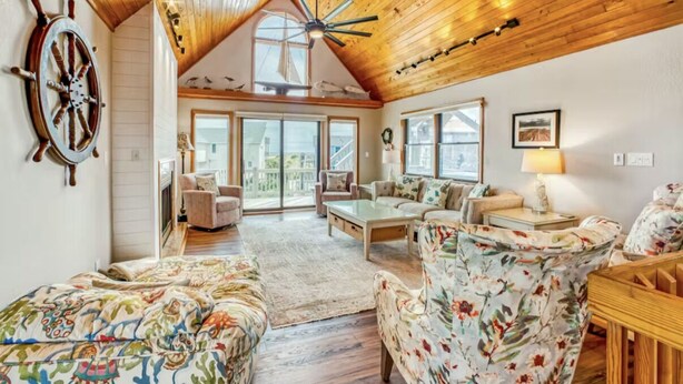 A spacious living room with a high ceiling and wooden beams, featuring a large sail wheel, a sofa set, and a coffee table. - Cozy Oceanside 3-bedroom house in fabulous Avon with incredible ocean views. (Avon)