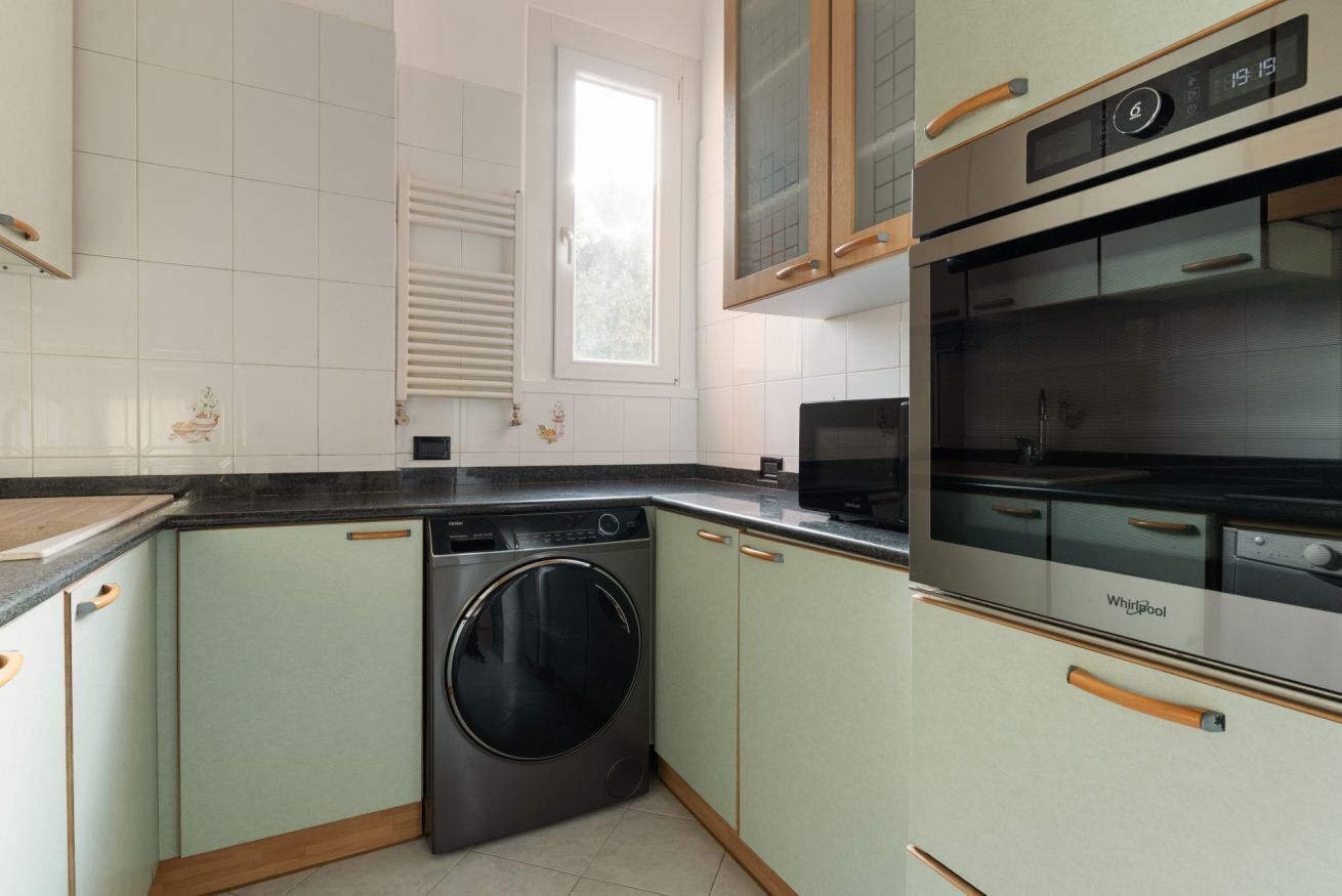 A kitchen with a washing machine, an oven, and a window.