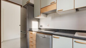 A kitchen with a refrigerator, dishwasher, and wooden cabinets. - GuestHost - Cozy 56 sqm apartment, located on the second floor of a building without an elevator.The accommodation is located in the San Siro area, an ideal neighbourhood for those looking for a quieter alternative to the city centre without giving up co (Milan)