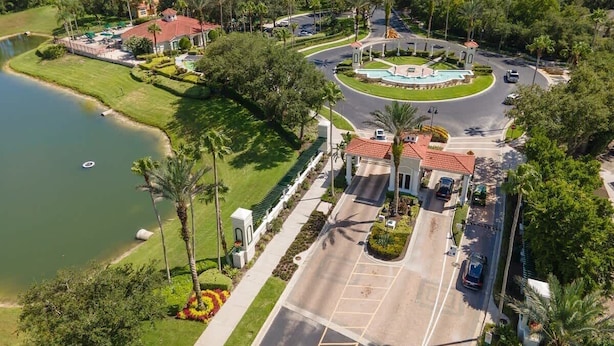 A golf course with a central clubhouse, a parking lot, and a lake. - 3BR Villa in Emerald Island Near Disney (Kissimmee)