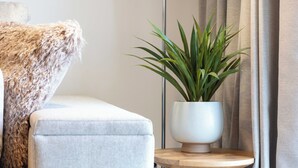 A modern living room with a light-colored sofa, a round wooden side table, and a potted plant. - Old Prestwick Point (Prestwick)
