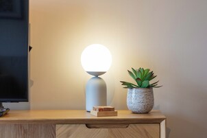 Un escritorio de madera con una televisión, una lámpara moderna y una planta en maceta.