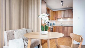 A modern kitchen with wooden cabinets, a round dining table, and a potted orchid. - Old Prestwick Point (Prestwick)