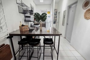 A narrow kitchen with a bar stool area, a refrigerator, and a welcome bag on the counter. - Casa Qodesh #1: Oasis Eco-Gem, Solar & Water (Arecibo)