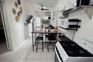 A kitchen with a gas stove, microwave, and a dining area with chairs. - Casa Qodesh #1: Oasis Eco-Gem, Solar & Water (Arecibo)