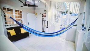 Eine Hängematte in einem Raum mit einer schwarzen Couch, einem Deckenventilator und einer weißen Tür.