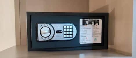 Un teclado de seguridad sobre una repisa, una tetera y una cafetera en una estante inferior.