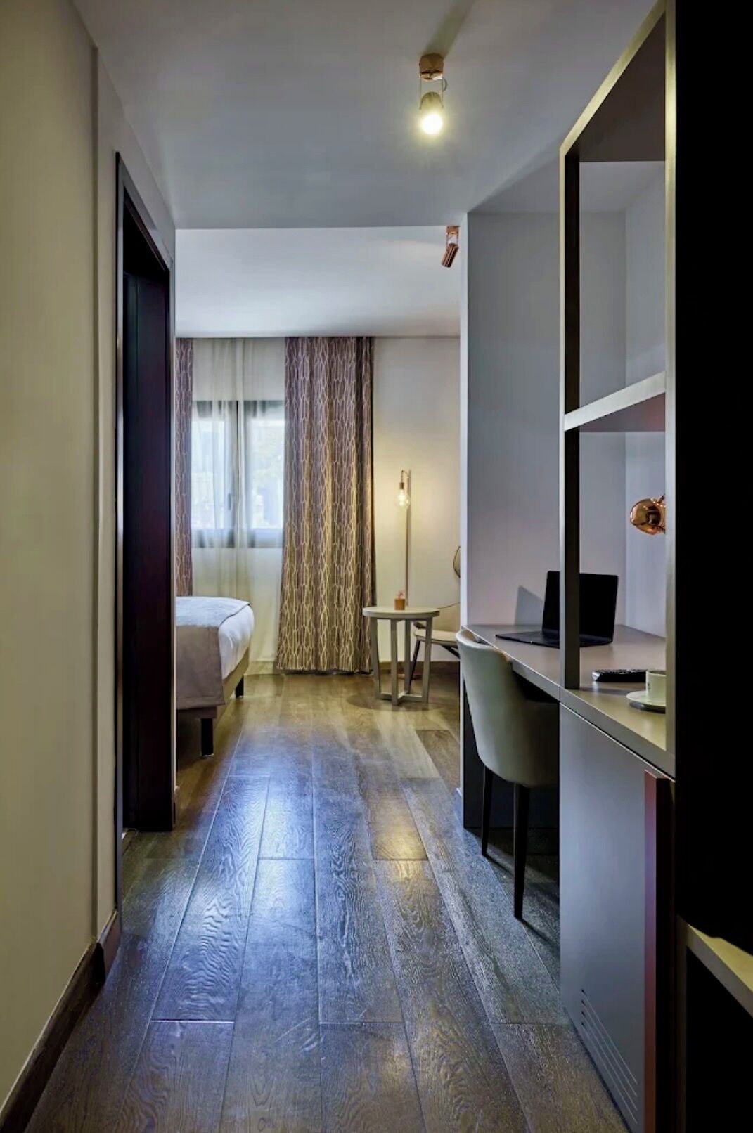 Une chambre d’hôtel avec un lit, un bureau, une chaise et un grand miroir.