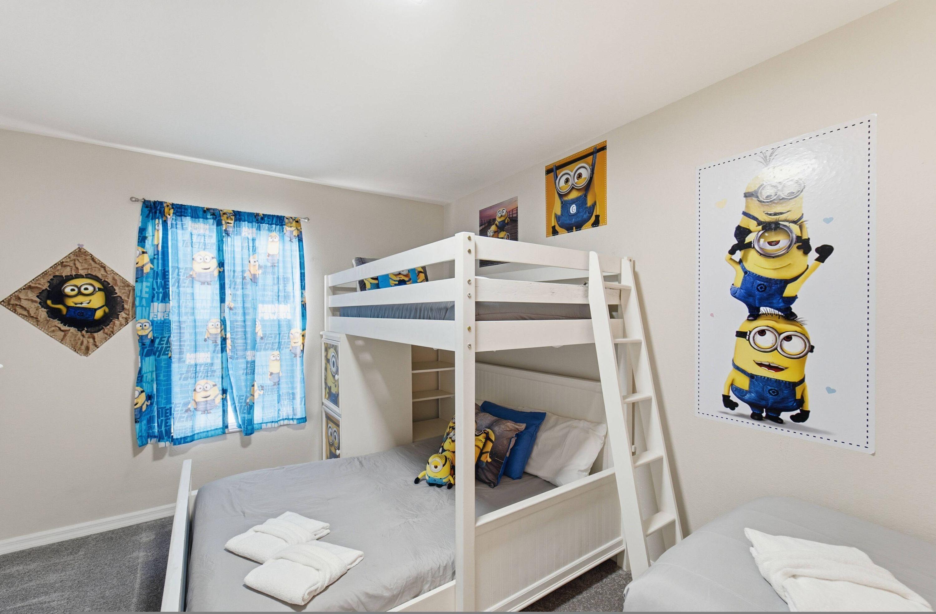 Habitación con literas decorada con un cortinero, un cartel y una obra de arte con temática de los Minions.