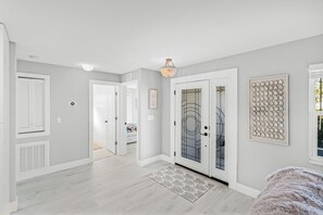 A hallway with a light gray wall, white door with a glass panel, and a decorative wall piece. - VRCC Villa Le Viva - charming coastal retreat (Cape Coral)
