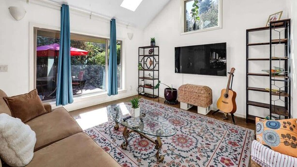 A living room with a sofa, a coffee table, a TV, and a guitar. - Peaceful Garden Cottage Near UofO (Eugene)