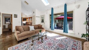 A living room with a sofa, coffee table, and patterned rug. - Peaceful Garden Cottage Near UofO (Eugene)