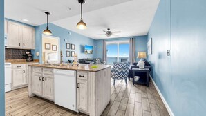A modern kitchen with a large island, white cabinetry, and a view to the outside. - 🏖️Beachfront | Gulf Views | 2BR Sterling Reef 505🏖️ (Panama City Beach)