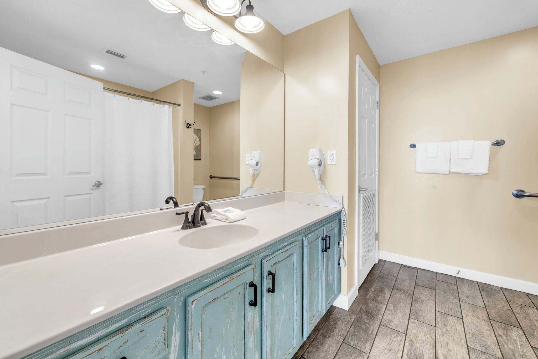 Une salle de bain avec un grand miroir, un lavabo et un porte-serviettes.